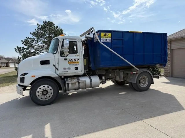 A large, empty blue ASAP Containers dumpster positioned on a construction site