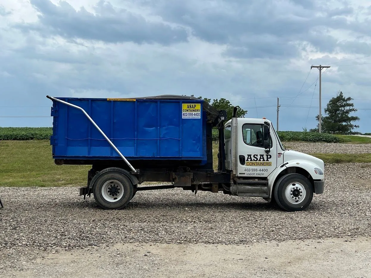 A blue ASAP Containers dumpster on a driveway in Columbus, NE