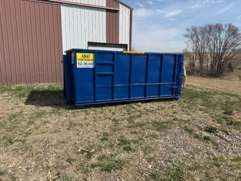 Blue ASAP Containers roll-off dumpster on a property, ready to be picked up